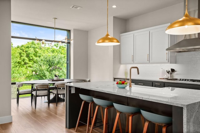 kitchen featuring pendant lighting, white cabinetry, tasteful backsplash, light stone countertops, and stainless steel gas cooktop