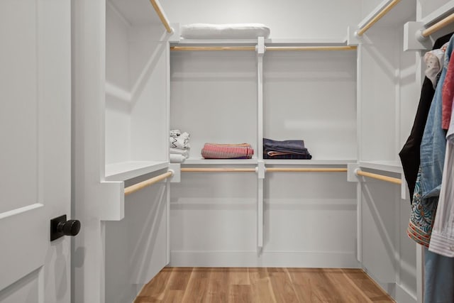 walk in closet with light hardwood / wood-style flooring