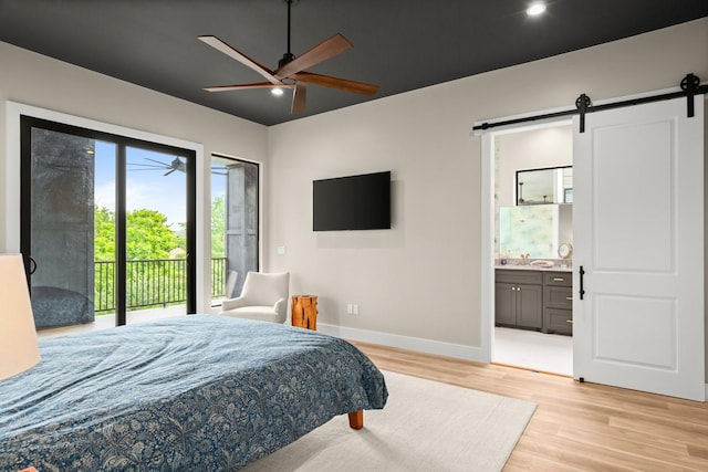 bedroom featuring ensuite bathroom, access to outside, ceiling fan, light hardwood / wood-style floors, and a barn door