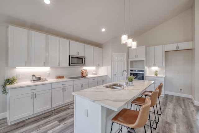 kitchen featuring pendant lighting, sink, appliances with stainless steel finishes, white cabinetry, and an island with sink