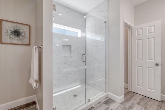 bathroom with a shower with door and wood-type flooring