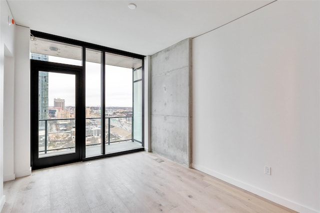 empty room with light hardwood / wood-style flooring and a wall of windows