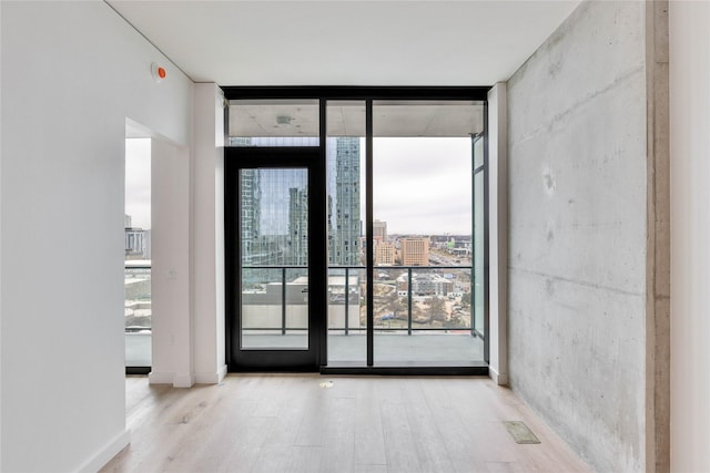 empty room with plenty of natural light, a wall of windows, and light hardwood / wood-style flooring