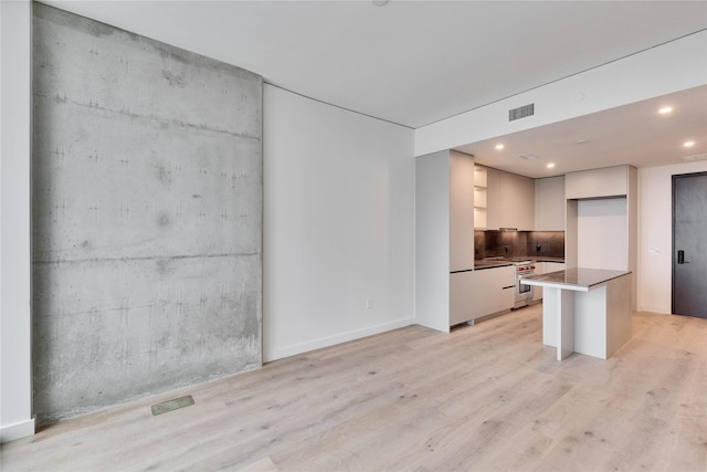 kitchen with white cabinetry, high end stove, and light hardwood / wood-style flooring