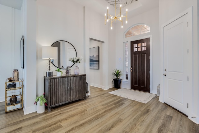 foyer entrance with a towering ceiling, light hardwood / wood-style floors, and a chandelier