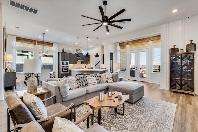 living room featuring french doors, ceiling fan, and light wood-type flooring