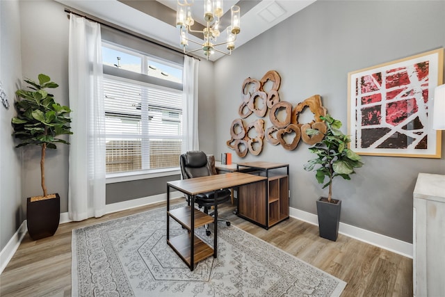 home office with a chandelier and light hardwood / wood-style floors