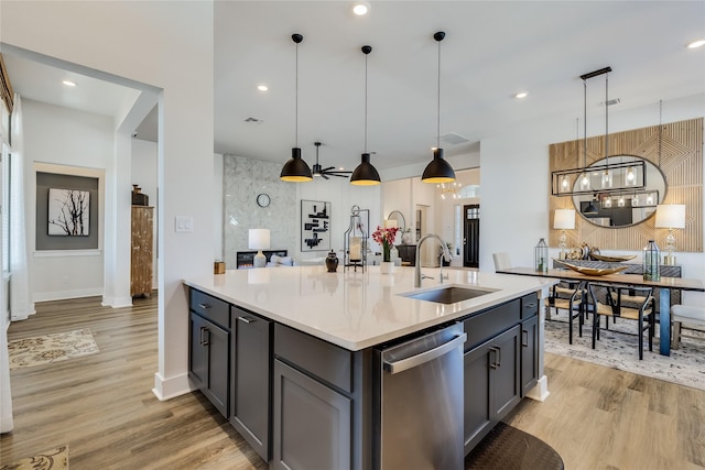 kitchen with sink, gray cabinetry, hanging light fixtures, stainless steel dishwasher, and a kitchen island with sink