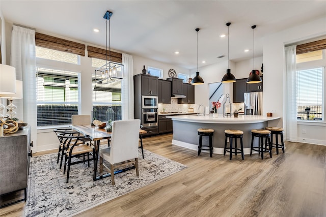 dining area featuring an inviting chandelier, sink, and light hardwood / wood-style floors