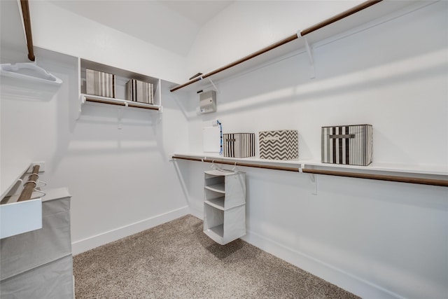 walk in closet with light colored carpet and vaulted ceiling