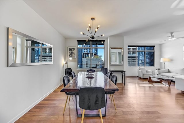 dining area with ceiling fan with notable chandelier and hardwood / wood-style floors