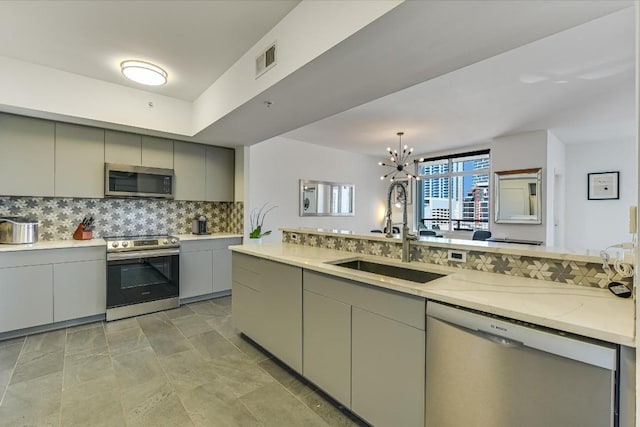 kitchen featuring gray cabinets, sink, decorative backsplash, stainless steel appliances, and light stone countertops