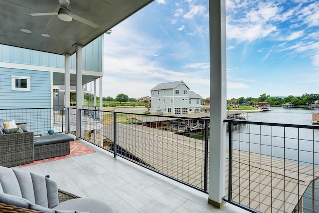 balcony with an outdoor living space, ceiling fan, and a water view