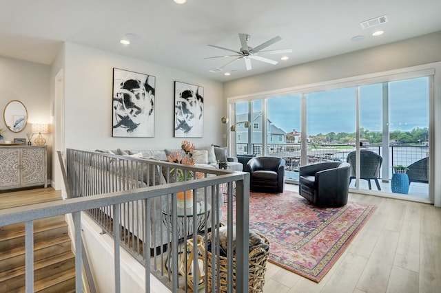 living room with a water view, ceiling fan, and wood-type flooring