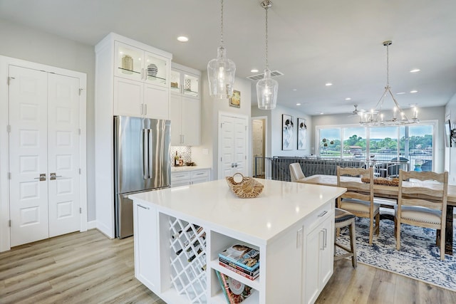 kitchen featuring white cabinetry, hanging light fixtures, stainless steel refrigerator, and a center island