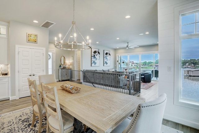 dining area with ceiling fan with notable chandelier and light wood-type flooring