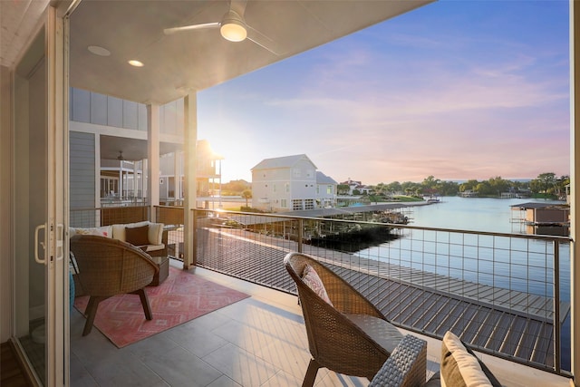 balcony at dusk with ceiling fan and a water view