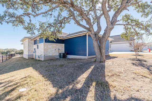 exterior space featuring a garage, a front lawn, and central air condition unit