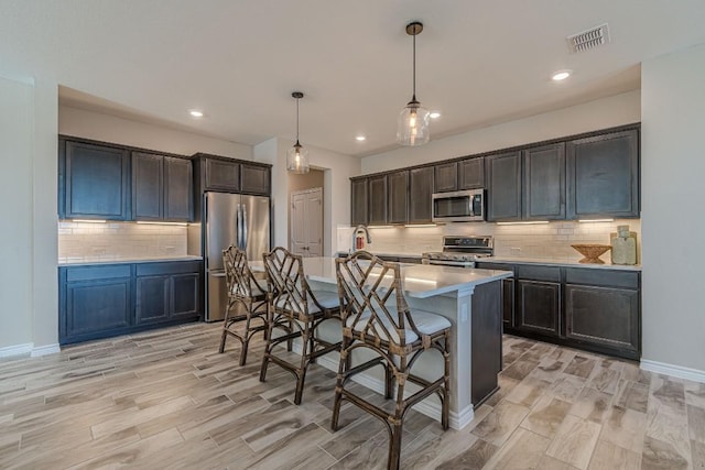 404 Eagle Dr, San Marcos, TX 78666 - kitchen with stainless steel appliances, a kitchen bar, wood tiled floors, decorative backsplash, and light countertops