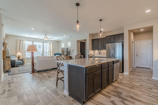 404 Eagle Dr, San Marcos, TX 78666 - kitchen with open floor plan, dark brown cabinetry, light wood finished floors, stainless steel appliances, and a kitchen breakfast bar