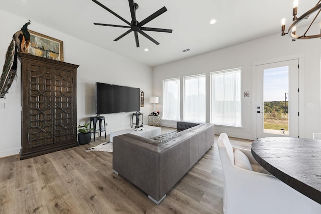 living room featuring ceiling fan with notable chandelier, plenty of natural light, and light hardwood / wood-style floors