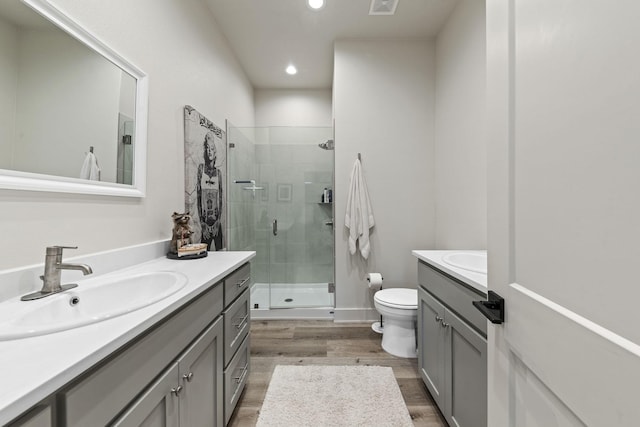 bathroom featuring vanity, hardwood / wood-style flooring, a shower with shower door, and toilet