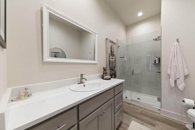 bathroom with wood-type flooring, toilet, vanity, and a shower with shower door