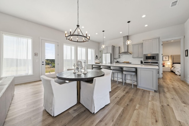 dining space featuring a healthy amount of sunlight, sink, and light hardwood / wood-style flooring