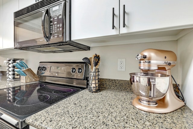 room details featuring white cabinetry, electric range, and light stone counters