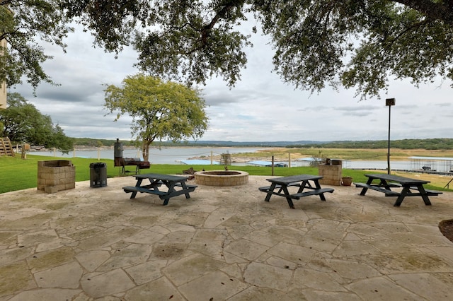 view of property's community with a patio area, an outdoor fire pit, and a water view