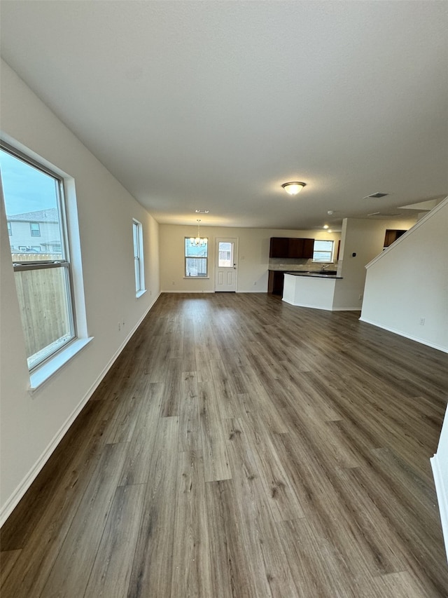 unfurnished living room with an inviting chandelier and wood-type flooring