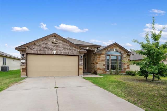 view of front of property with a garage, a front yard, and central air condition unit