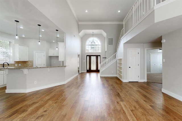 foyer featuring ornamental molding, sink, light wood-type flooring, and a high ceiling