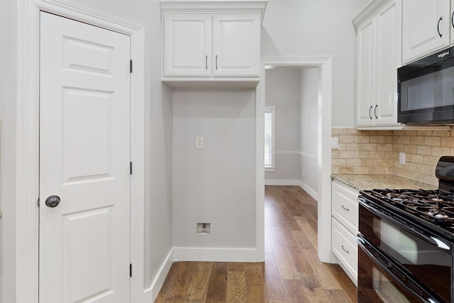 kitchen featuring backsplash, white cabinets, light stone counters, and black appliances