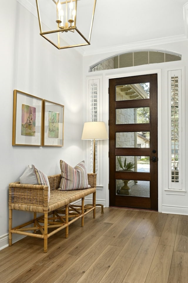 entryway featuring a notable chandelier, crown molding, and wood-type flooring