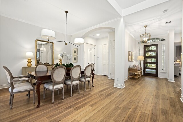 dining space with crown molding, wood-type flooring, and a chandelier