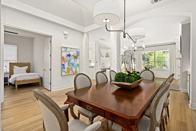 dining space with ornamental molding, a notable chandelier, and light hardwood / wood-style flooring