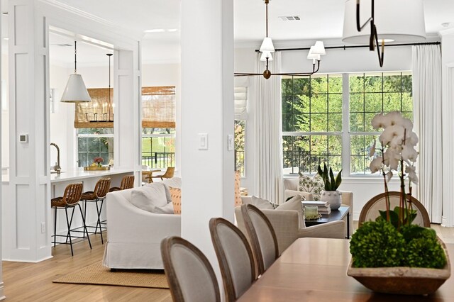 interior space with a notable chandelier, ornamental molding, and light hardwood / wood-style floors