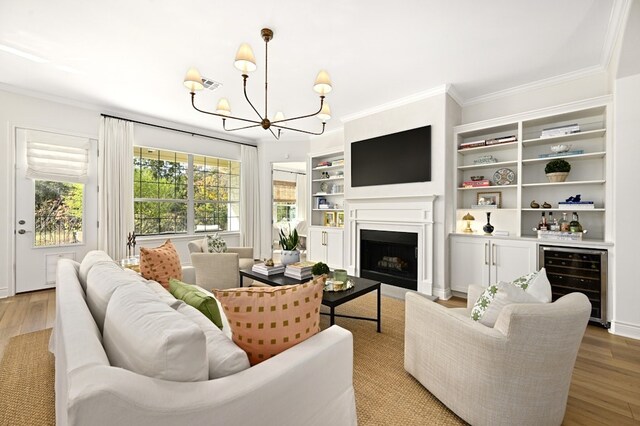 living room with built in features, an inviting chandelier, wine cooler, and light hardwood / wood-style floors