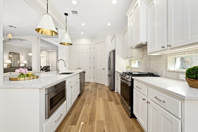 kitchen featuring sink, appliances with stainless steel finishes, hanging light fixtures, white cabinets, and custom exhaust hood