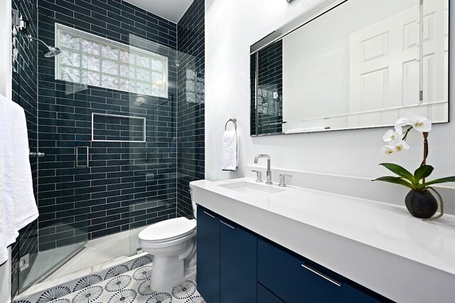 bathroom featuring vanity, tile patterned floors, toilet, and tiled shower