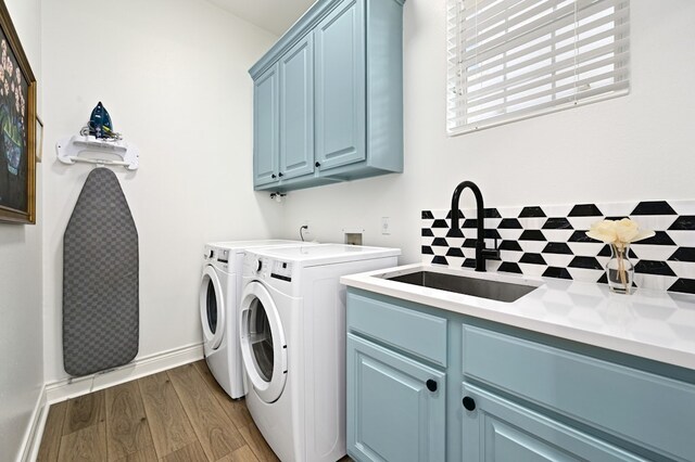 laundry room with hardwood / wood-style flooring, cabinets, sink, and washing machine and clothes dryer