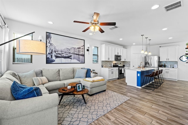 living room with sink, ceiling fan, and light hardwood / wood-style flooring