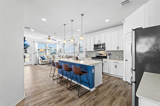 kitchen with appliances with stainless steel finishes, a breakfast bar, an island with sink, sink, and white cabinets