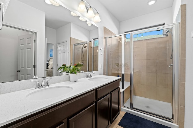 bathroom featuring a shower with door and vanity