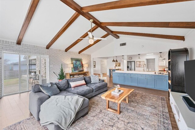 living room featuring sink, beam ceiling, and light hardwood / wood-style floors