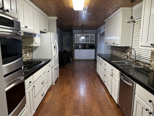 kitchen with tasteful backsplash, white cabinetry, stainless steel appliances, and decorative light fixtures