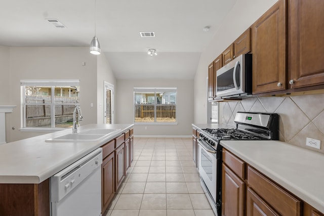 kitchen featuring lofted ceiling, sink, light tile patterned floors, stainless steel appliances, and a kitchen island with sink