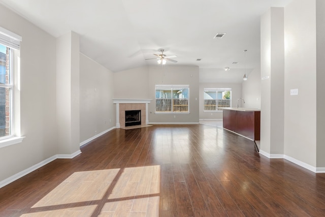 unfurnished living room with ceiling fan, lofted ceiling, dark hardwood / wood-style flooring, and a tiled fireplace