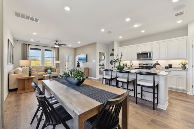 dining space featuring sink, ceiling fan, and light hardwood / wood-style flooring